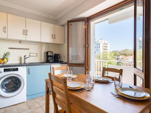 une cuisine avec une table en bois, des chaises et un lave-linge. dans l'établissement Apartment Clos St Martin-5 by Interhome, à Biarritz