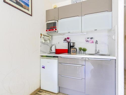 Elle comprend une petite cuisine avec des placards blancs et un réfrigérateur. dans l'établissement Studio Ciel de Fabron by Interhome, à Nice