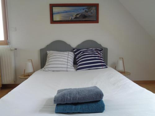 un lit blanc avec deux oreillers dessus dans l'établissement Séjour détente en famille à deux pas de la plage, à Saint-Pol-de-Léon