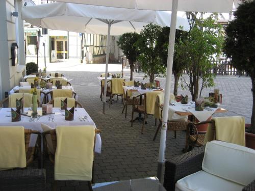 a row of tables with yellow chairs and an umbrella at Hotel Werratal in Bad Sooden-Allendorf