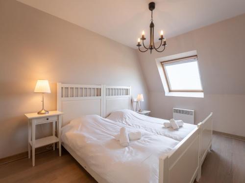 a white bedroom with a large white bed with two pillows at Apartment Albatros with parking by Interhome in Bredene