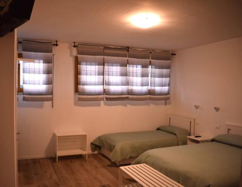 a bedroom with two beds and two windows at RelaxArte Cisanello Pisa in Pisa