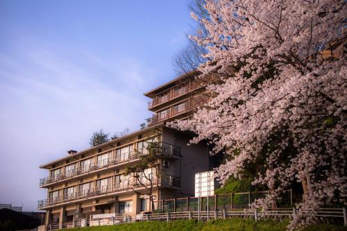 an apartment building with aakura tree in front of it at Yuyaruru Saisai in Kanazawa