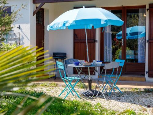 une table et des chaises sous un parapluie bleu dans l'établissement Holiday Home Le Predaire by Interhome, à Pornic