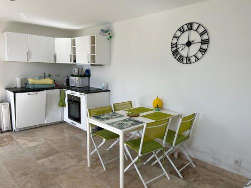 une cuisine avec une table et des chaises et une horloge au mur dans l'établissement Appartement Cavalaire sur Mer, à Cavalaire-sur-Mer