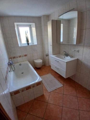 a bathroom with a tub and a sink and a toilet at Ferienhaus Nosbers in Kleinlangenfeld