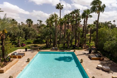 a swimming pool in a resort with palm trees at Palais Namaskar in Marrakech