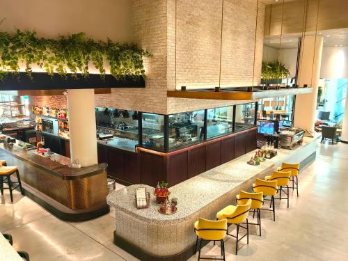 a restaurant with a bar with yellow chairs at Millennium Airport Hotel Dubai in Dubai