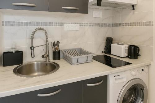 a kitchen with a sink and a washing machine at Exclusive Private Apartment by Warilco - Pleyel 25 m2 - À 1 minute de la station métro Carrefour Pleyel in Saint-Denis
