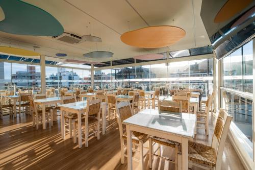 a restaurant with tables and chairs and windows at Flat Summer in Florianópolis