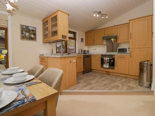 a kitchen with wooden cabinets and a table with chairs at Herdwick Lodge in Windermere