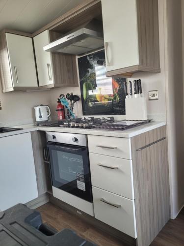 a small kitchen with a stove and white cabinets at LUXURY CARAVAN 10 mins TO BEACH in Hull