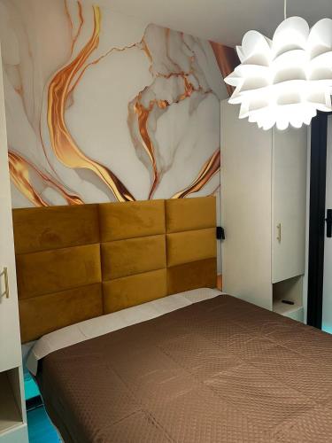 a bedroom with a bed with a painting on the wall at ANTARES - Piazza Fontana - in Lignano Sabbiadoro