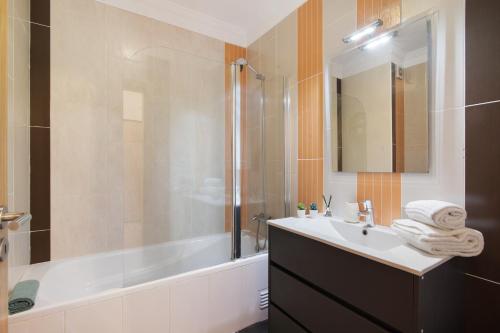 Un baño con lavabo, ducha y bañera. en Apartamento T2 Rio E Mar, en Vila Real de Santo António