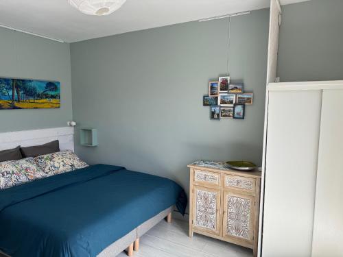 - une chambre avec un lit bleu et une armoire en bois dans l'établissement Studio vue sur jardin à 3 mn en voiture de la mer, à Fouesnant