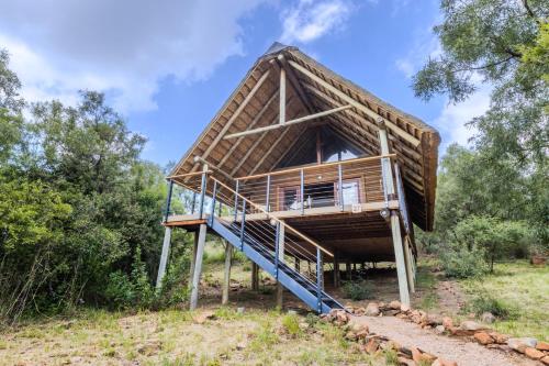 a thatch roofed house with a staircase in a field at Cradle Boutique Hotel in Lanseria