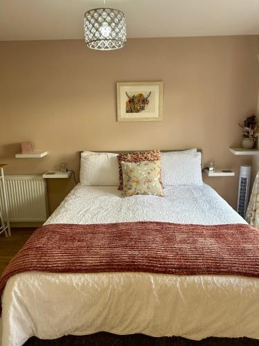 a bedroom with a large bed with white sheets at Stepping Stone in Fort William