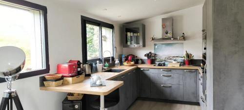 une cuisine avec des armoires bleues, un évier et une fenêtre dans l'établissement Penn Ar Bed, à Paimpol