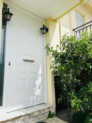 a white door on a house with a bush at Άρπυια in Kakóvatos
