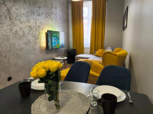 a dining room with a table with yellow chairs at Tabago Studio 32 Brzeg Wolności in Brzeg