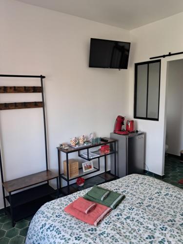 a bedroom with a bed and a tv on the wall at Gentil coquelicot in Mirepoix