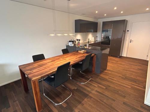 a kitchen and dining room with a wooden table and chairs at Moderne Businesswohnung, chic & zentral in Wollerau