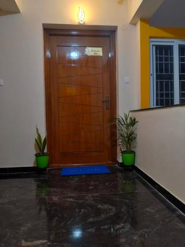 a wooden door in a room with two potted plants at SaiNivas Satyam in Chennai