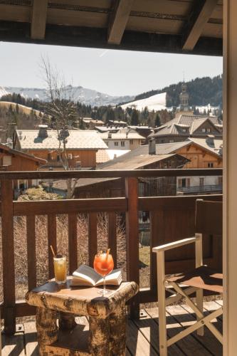 a table with a book and a drink on a balcony at Lodge Park in Megève