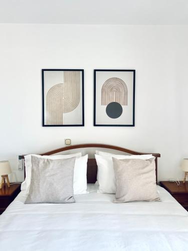 a bedroom with a white bed with three pictures on the wall at Topophilia Villa in Monemvasia