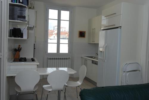 - une cuisine avec une table blanche et des chaises blanches dans l'établissement Forville F4, à Cannes