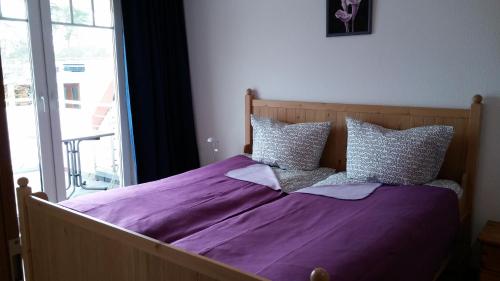 ein Bett mit lila Bettwäsche und Kissen in einem Schlafzimmer in der Unterkunft Residenz Zum Kronprinzen in Bad Saarow
