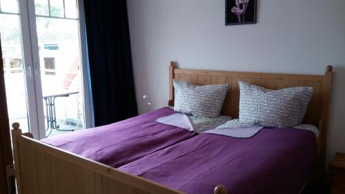 a bed with purple sheets and pillows in a bedroom at Residenz Zum Kronprinzen in Bad Saarow