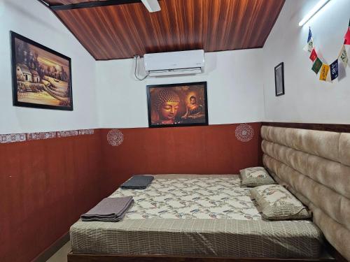 a small bedroom with a bed and posters on the wall at Farmhouse with Pool - Kalavady Farmstay in Baindūru