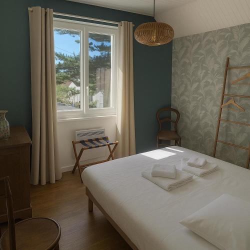 une chambre avec un lit avec des draps blancs et une fenêtre dans l'établissement Maison à 2 kms de la Plage, à Plomeur