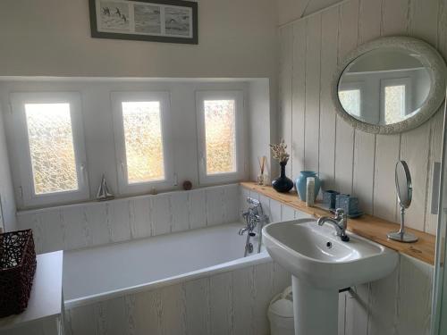 une salle de bain avec une baignoire, un lavabo et un miroir dans l'établissement Maison à 2 kms de la Plage, à Plomeur