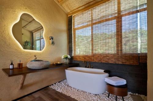 a bathroom with a tub and a sink and a mirror at penida in Tianxin