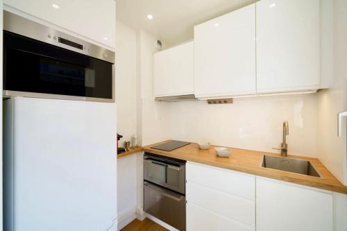 a kitchen with white cabinets and a sink at 100m Plage Antibes - Juan Appartement Stella Cœur in Antibes