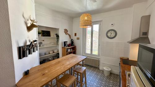 une cuisine avec une table et une horloge au mur dans l'établissement Le Pan de la Grange, Le Mont-Dore 5pers, à Le Mont-Dore