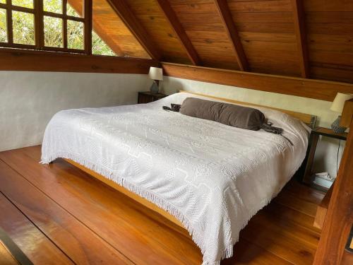 a bed in a room with a wooden ceiling at Charming Cosy Chirripó Mountain Riverfront Cottage in Canaán