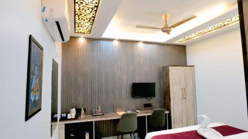 a room with a bed and a desk with a television at Hotel Shivsudhaa in Varanasi