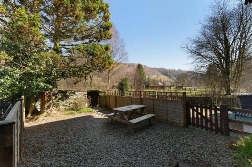 a wooden bench sitting in front of a fence at Heron View Cottage in Grasmere