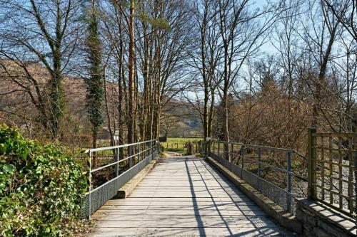 a bridge over a field with trees and a fence at Heron View Cottage in Grasmere