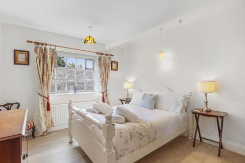 a bedroom with a white bed and a window at Spindlestone Cottage - North East Escapes in Bamburgh