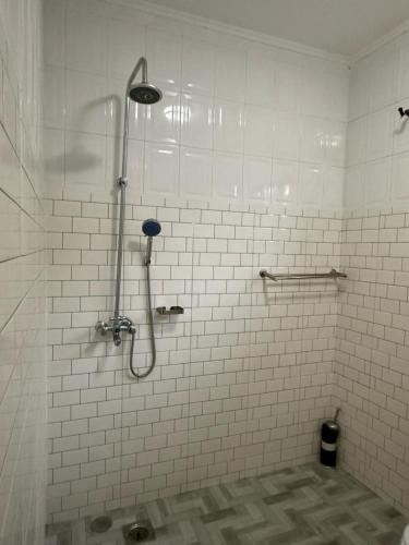 a shower in a bathroom with white tiles at Logic stays 3 bedroom Arusha, Njiro in Arusha