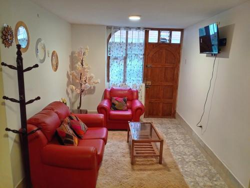 a living room with two red couches and a tv at El Descanso in Cusco