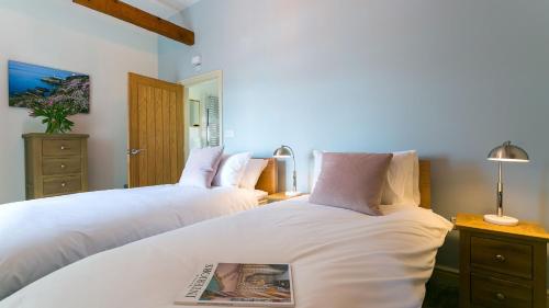 a bedroom with two beds with a book on the bed at Bwthyn Gwenllyr in Llangadwaladr