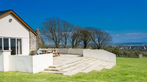 a patio with a table and a bench on a lawn at Bwthyn Gwenllyr in Llangadwaladr
