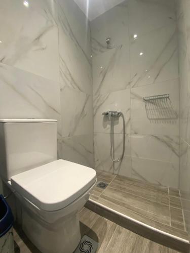a white bathroom with a toilet and a shower at Prionas Studios in Paralía Skotínis