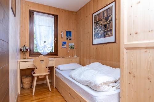 a small bedroom with a bed and a desk at Chalet Baranci in Pozza di Fassa