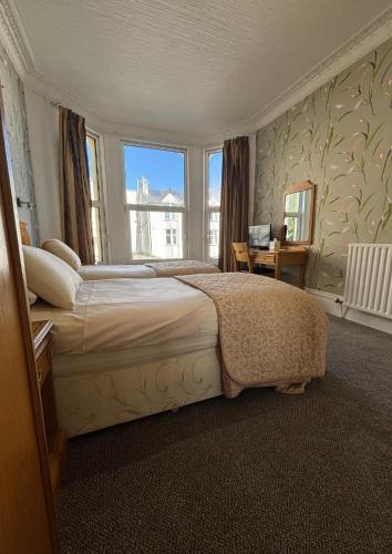 a bedroom with a large bed with a large window at Welbeck Hotel & Apartments IOM in Douglas